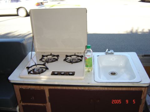 1993 Ford Bronco - The interior of a pop-up tent trailer shows a compact kitchen area with a stove and sink.