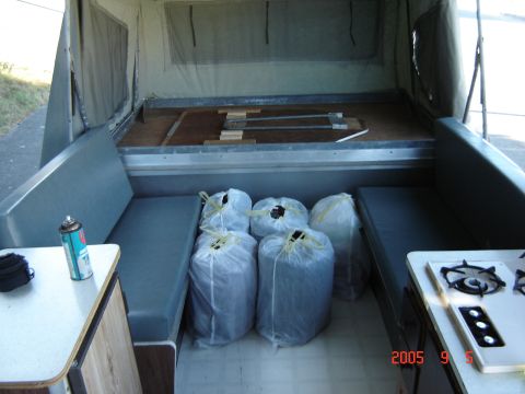 1993 Ford Bronco - Interior view of a pop-up tent trailer, showing seating, storage bags, and a propane stove.