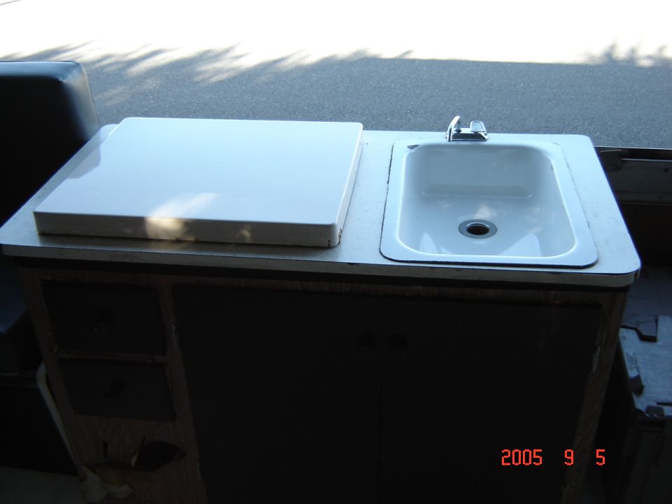 Sink and white countertop with a faucet, inside a dark cabinet