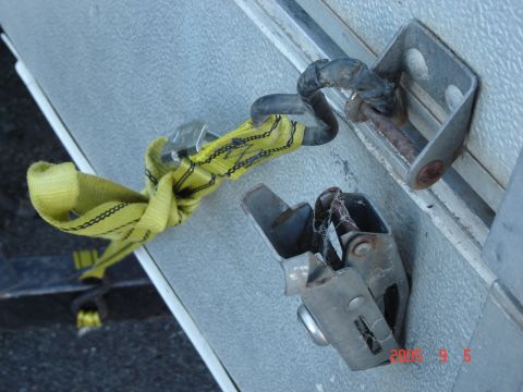 1993 Ford Bronco - Close-up of a yellow tie-down strap connected to a trailer's securing point.