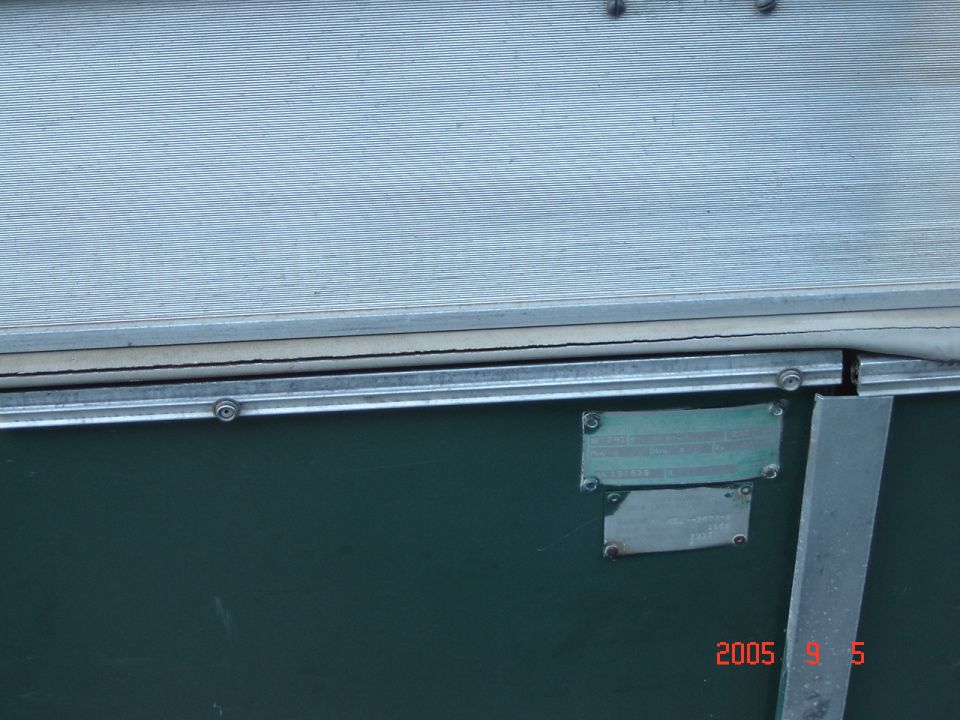 Close-up of two metal plates attached to the side of a dark green trailer