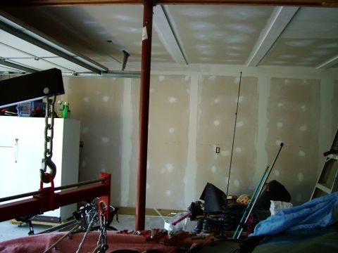 2003 Ford Mustang - Interior view of a garage with an engine hoist, unfinished drywall, and various tools and equipment.