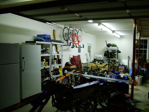 2003 Ford Mustang - A cluttered garage scene contains motorcycles, bicycles, shelving, and appliances.
