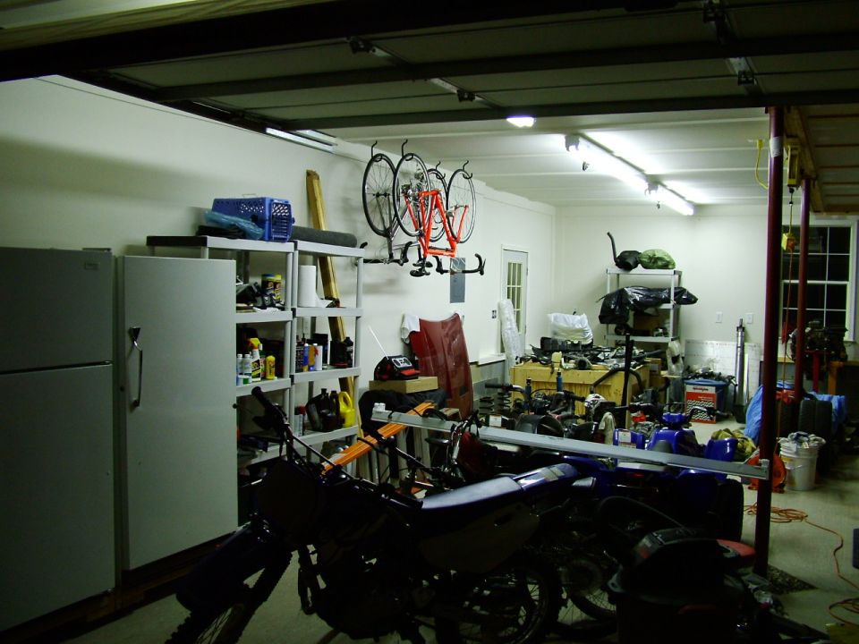 Garage interior with two motorcycles in the foreground and bicycles hanging on the wall