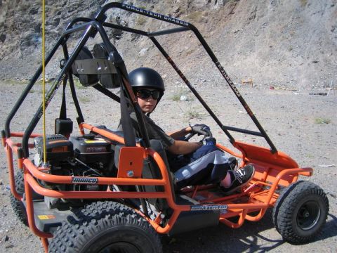 1994 Ford Bronco - A child drives an orange go-kart on a dirt track, with a rocky hillside in the background.