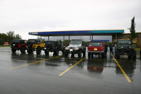 2003 Jeep TJ - Multiple Jeeps are parked in a line at a Tesoro gas station on a wet day.