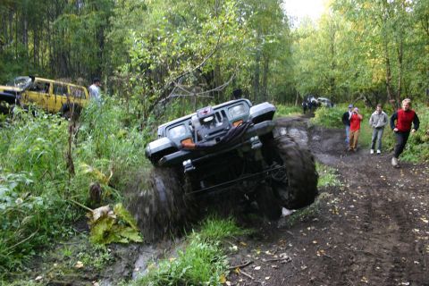 2003 Jeep TJ - A 2003 Jeep Wrangler TJ tackles a challenging muddy off-road course with spectators nearby.