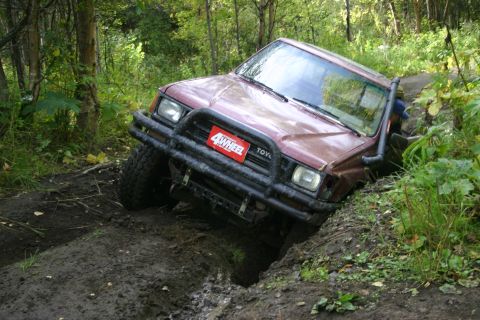 2003 Jeep TJ - A maroon Toyota 4Runner navigates a challenging muddy trail, equipped with off-road accessories.