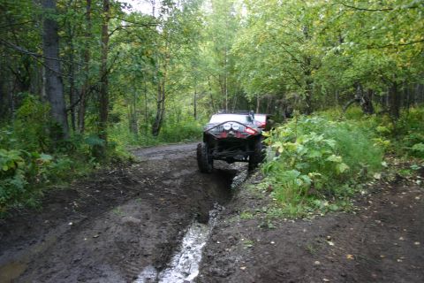 2003 Jeep TJ - This 2003 Jeep TJ is shown driving through a muddy off-road trail surrounded by trees.