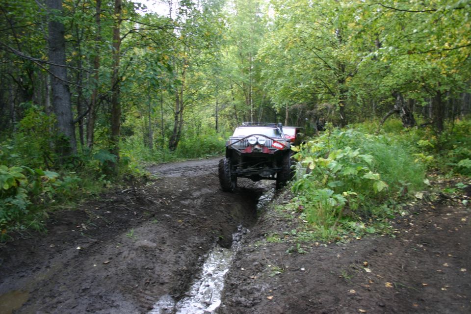 2003 Jeep TJ navigating a deep mud rut on a wooded trail