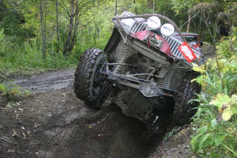 2003 Jeep TJ - An off-road vehicle navigates a challenging muddy terrain, its suspension and tire grip.