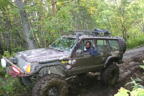 2003 Jeep TJ - A driver navigates a muddy trail in a modified Jeep Cherokee XJ.