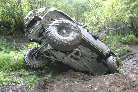 2003 Jeep TJ - A 2003 Jeep TJ is stuck on its side in a muddy off-road environment.