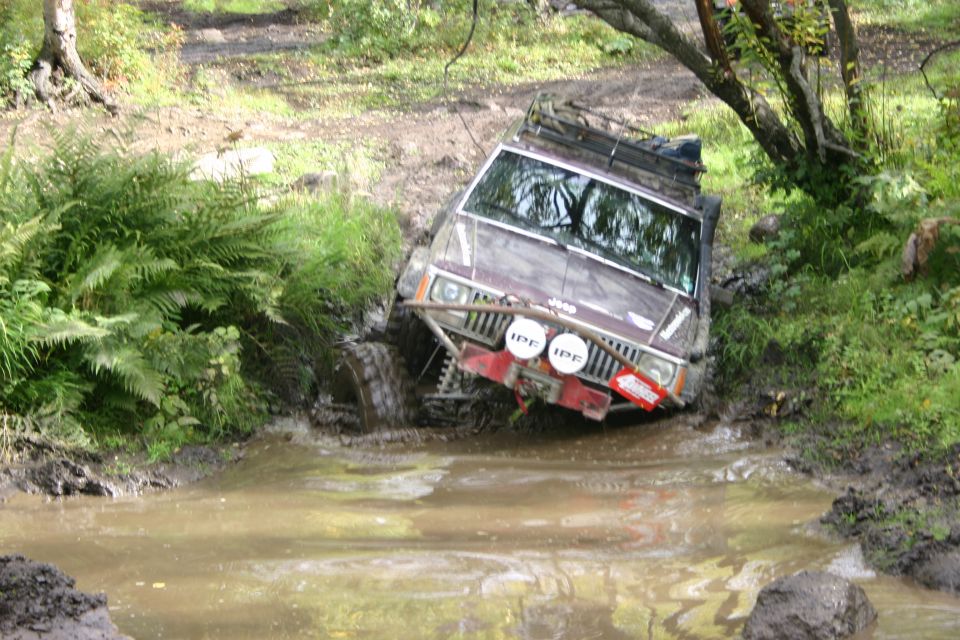 Maroon Jeep Cherokee XJ stuck in mud with IPF lights and roof rack
