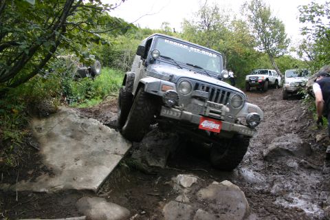 2003 Jeep TJ - A Jeep TJ tackles a challenging off-road course, demonstrating its capability on rough terrain.