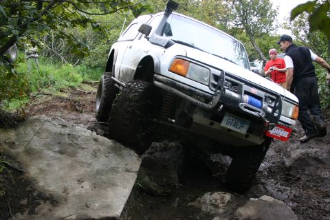 2003 Jeep TJ - Off-road SUV tackling a challenging rocky and muddy course with a winch and snorkel.