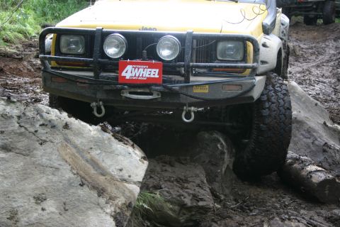 2003 Jeep TJ - This Jeep Cherokee XJ is tackling a difficult off-road course with large rocks and mud.