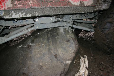 2003 Jeep TJ - Vehicle suspension and tire making contact with a large rock during off-road driving.