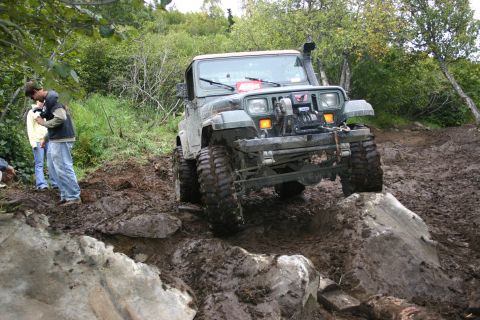 2003 Jeep TJ - A modified Jeep Wrangler navigates a challenging off-road course with steep inclines and muddy terrain.