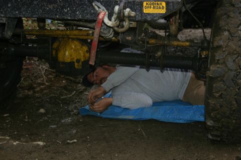 2003 Jeep TJ - Man works on the axle of an off-road vehicle, which has a 'Kodiak Off-Road' sticker.