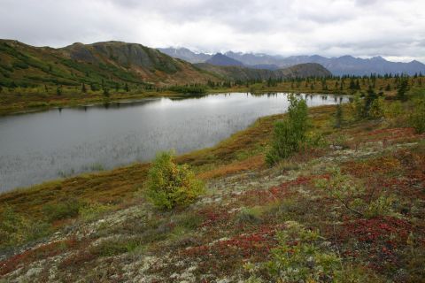 2003 Jeep TJ - A lake reflects the cloudy sky, surrounded by hillsides covered in autumn foliage and distant mountains.