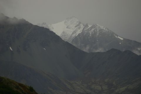 2003 Jeep TJ - A vast mountain range stretches across the frame, shrouded in mist and clouds.