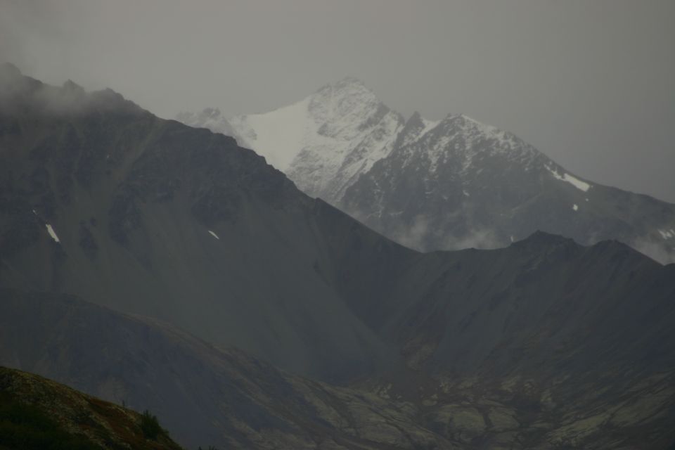 Jagged mountain peaks under a cloudy sky, with snow on the highest summit