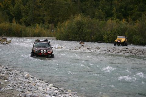 2003 Jeep TJ - Two Jeep Wranglers navigate a rocky riverbed, one brown and one yellow.