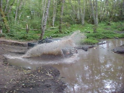 1992 Ford Ranger - A 1992 Ford Ranger navigates a muddy off-road course, creating a large splash as it drives through water.
