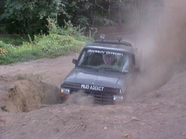 Truck with 'MUD ADDICT' on the hood stuck in a muddy ditch