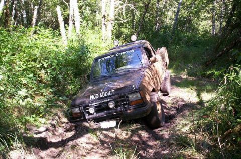 1992 Ford Ranger - This truck is deep in the mud on a wooded trail, with stickers indicating it's for off-roading.