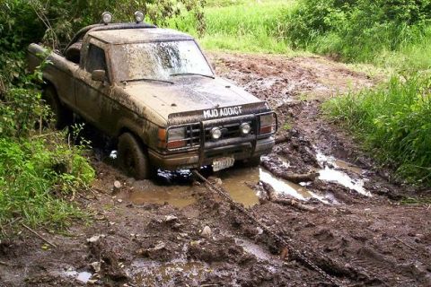 1992 Ford Ranger - A heavily mud-splattered 1989 Ford Ranger is stuck in a muddy off-road track, with a tow chain attached.