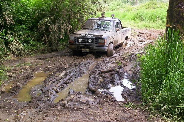 1992 Ford Ranger stuck in mud on a trail, with 'MUD ADDICT' decal on hood
