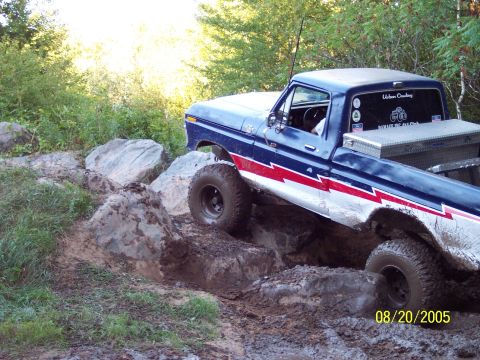 1977 Ford F-150 - This 1977 Ford F-150 is shown tackling a challenging off-road course with large rocks and mud.