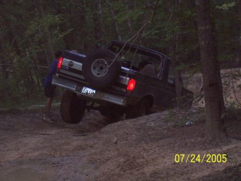 1993 Ford Bronco - A 1993 Ford Bronco navigates a challenging off-road trail, with a helper providing assistance from the rear.