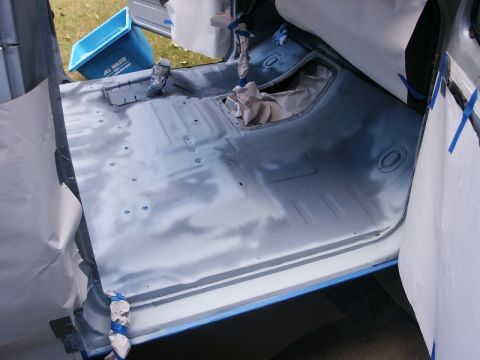 1982 Ford Bronco - The interior of a vehicle is prepared for a spray-in liner, with masking and primer visible on the floor.