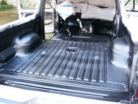 1982 Ford Bronco - Applying spray-in liner to a truck bed. The interior is visible with doors open.