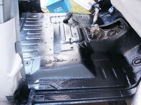 1982 Ford Bronco - The interior floor of a vehicle has been coated with a black spray-in liner, creating a textured protective surface.