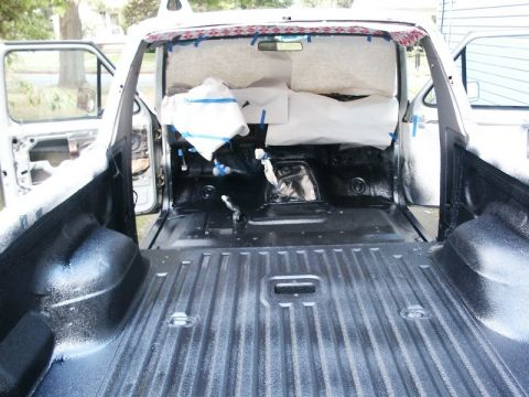1982 Ford Bronco - The bed of a pickup truck is shown with a freshly applied spray-in liner, with the interior cab also visible.