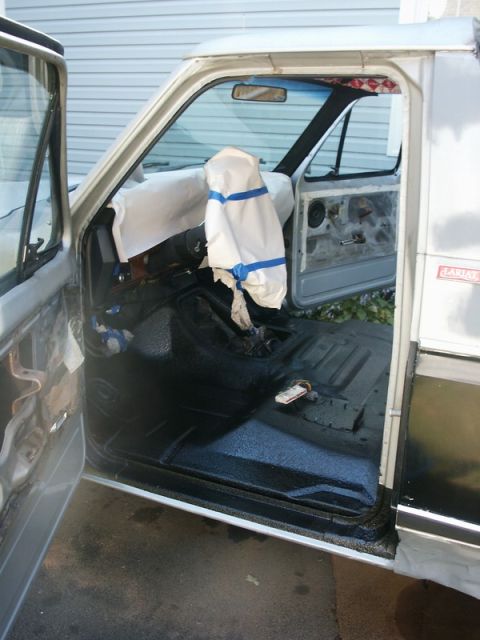 1982 Ford Bronco - The interior of a pickup truck is shown with the doors open, revealing the floor and a covered dashboard.