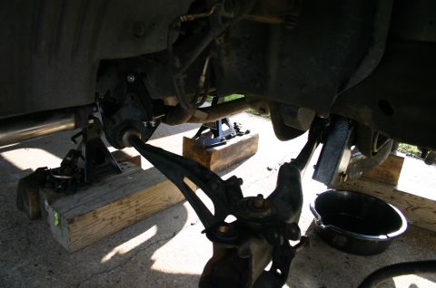 1994 Ford Bronco - Close-up view of the underbody suspension system, supported by jack stands and wooden blocks.
