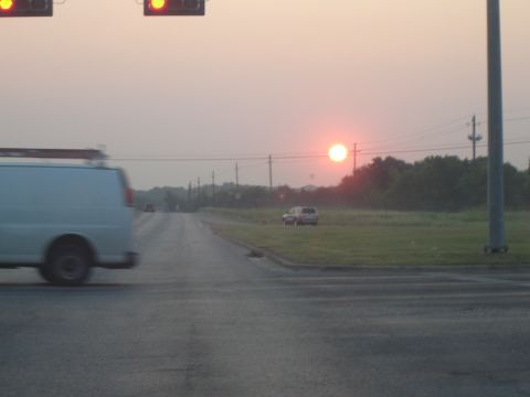 1988 Ford LTD Crown Victoria - A white van travels down a road during a sunset, with a single SUV visible in the distance on the right.