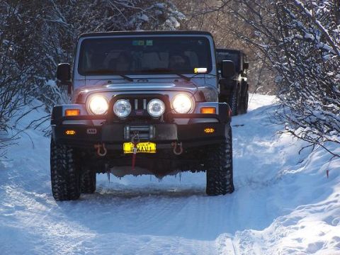 2003 Jeep TJ - Two Jeeps navigate a snow-covered path surrounded by trees.