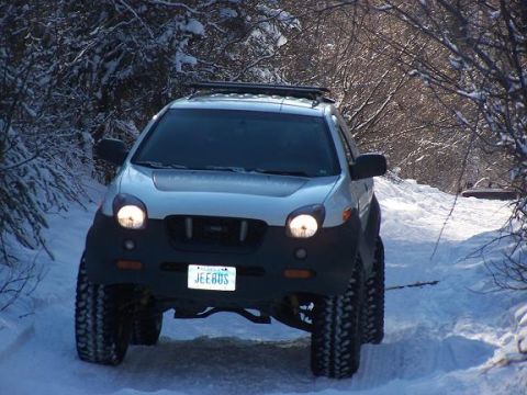 2003 Jeep TJ - Isuzu VehiCROSS navigates a snowy trail with its headlights on.