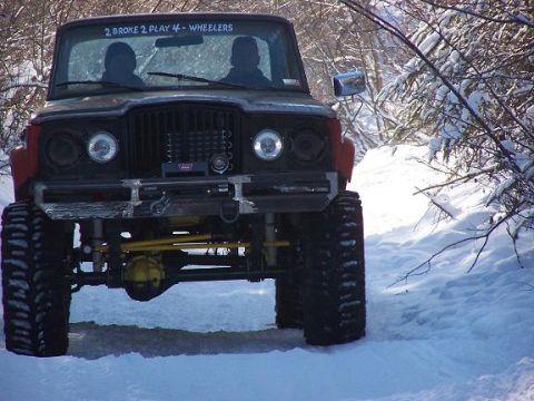 2003 Jeep TJ - A modified Jeep navigates a snowy trail, its large tires and aftermarket parts evident.