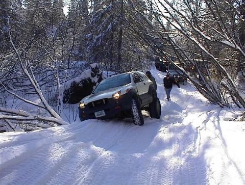 2003 Jeep TJ - Multiple SUVs navigate a snow-covered forest path.