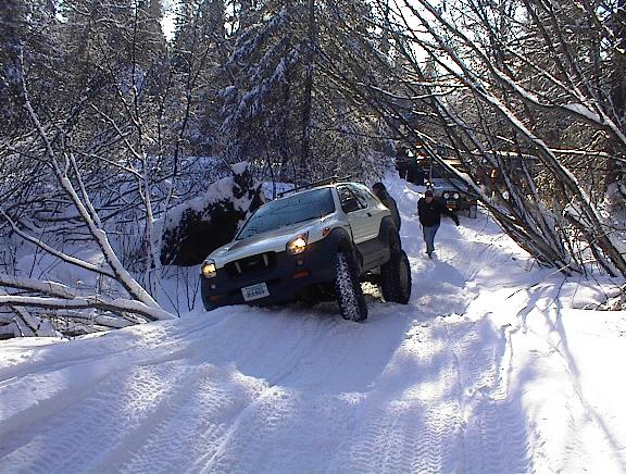 White SUV with large tires on a snowy trail, front view