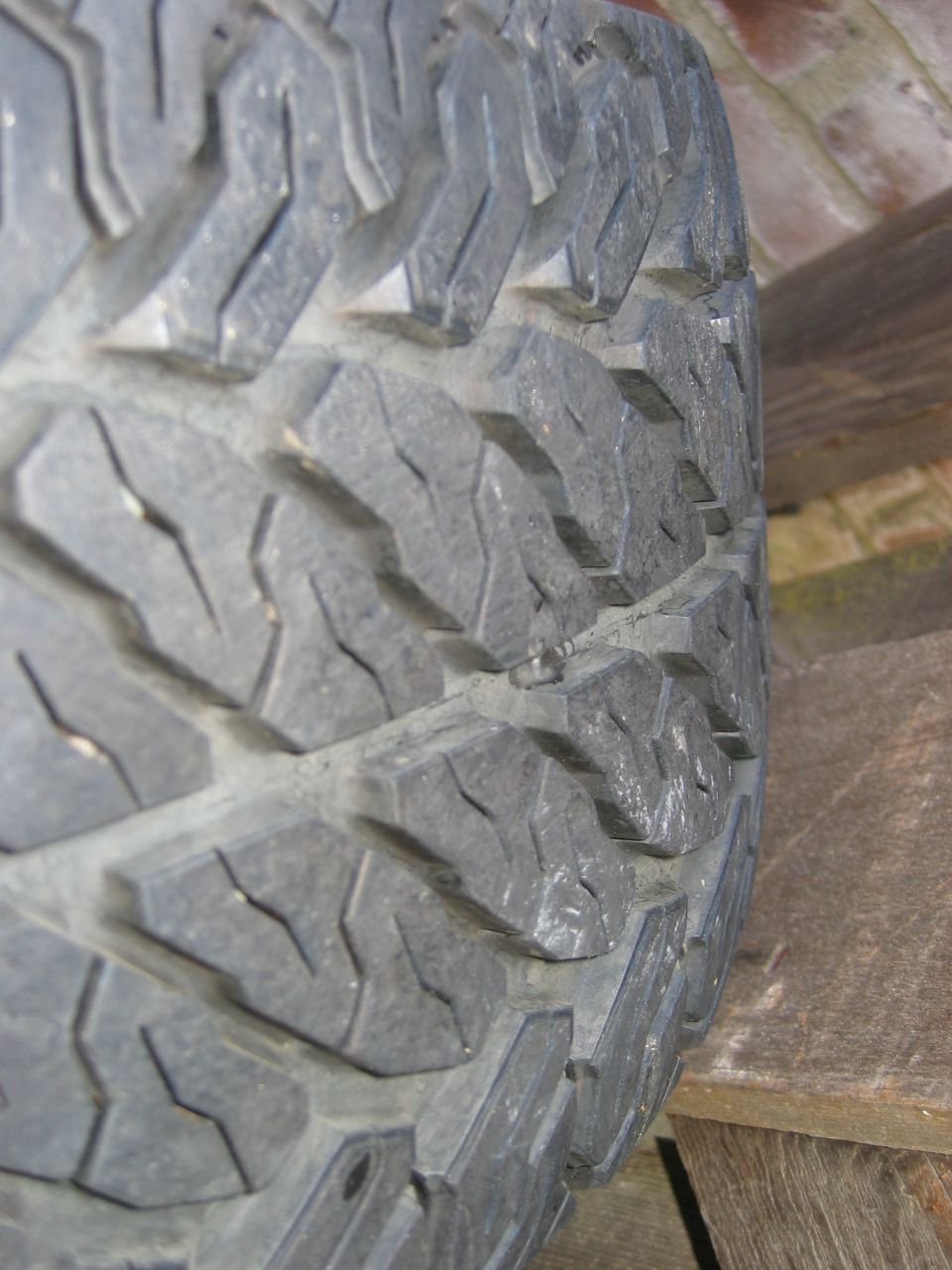 Tread face of an aggressive all-terrain tire resting on a wood pallet