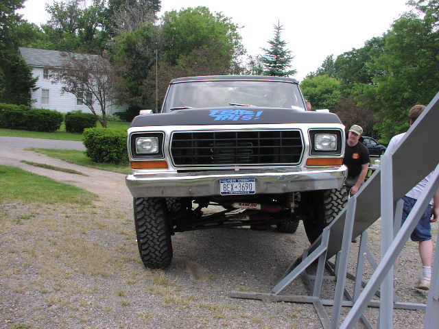 Black lifted 1978-79 Ford truck with blue lettering being driven onto a ramp