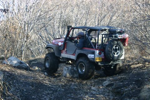 2003 Jeep TJ - A red 2003 Jeep TJ navigates a rocky trail with a spare tire on the back.